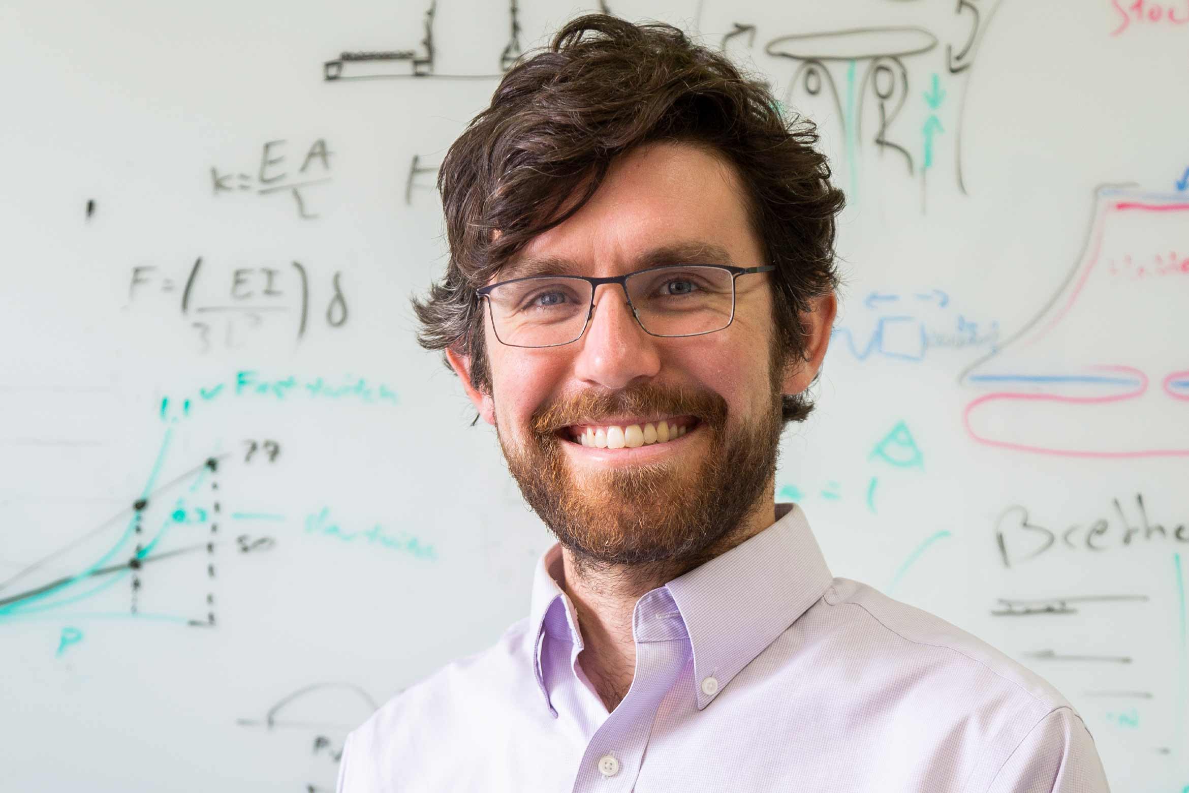 Elliot Hawkes standing in front of a white board